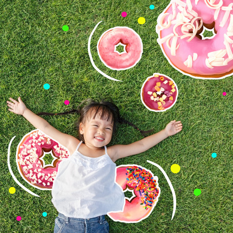 Kid lying on grass with donuts